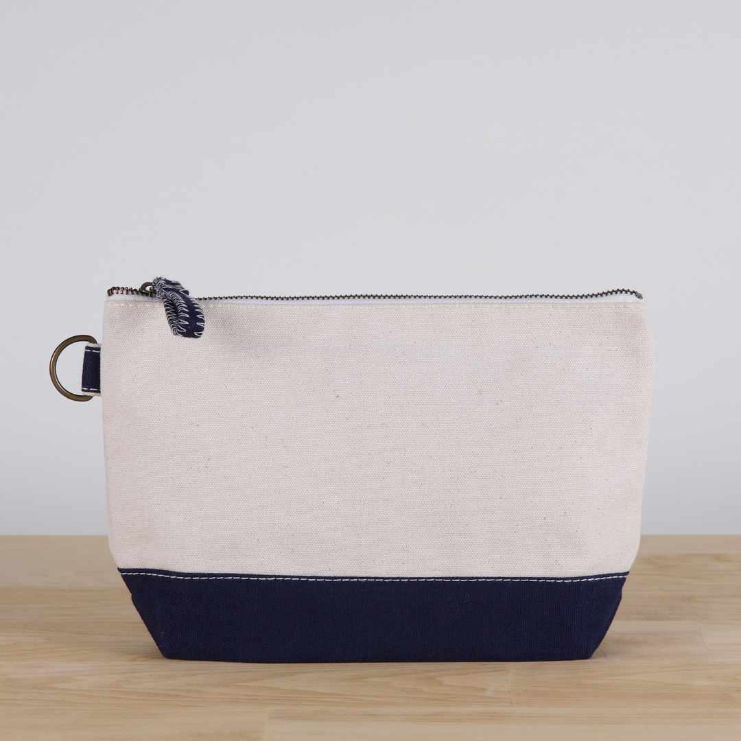 Beige and navy pouch on a wooden surface with a light gray background