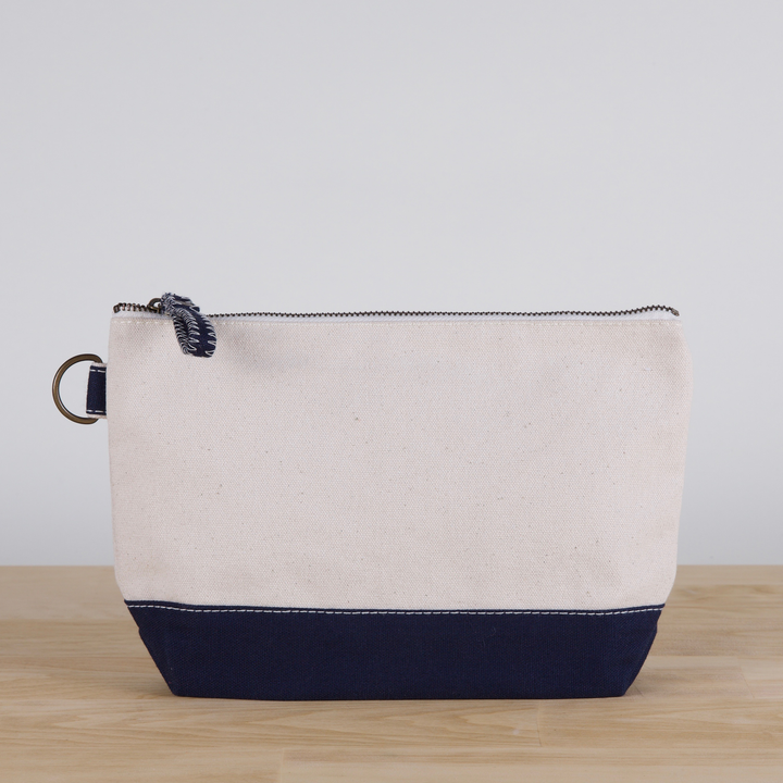 Beige and navy pouch on a wooden surface with a light gray background