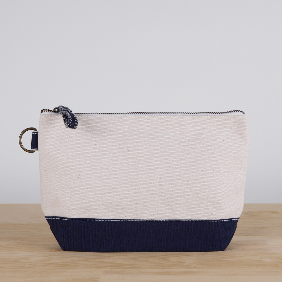Beige and navy pouch on a wooden surface with a light gray background
