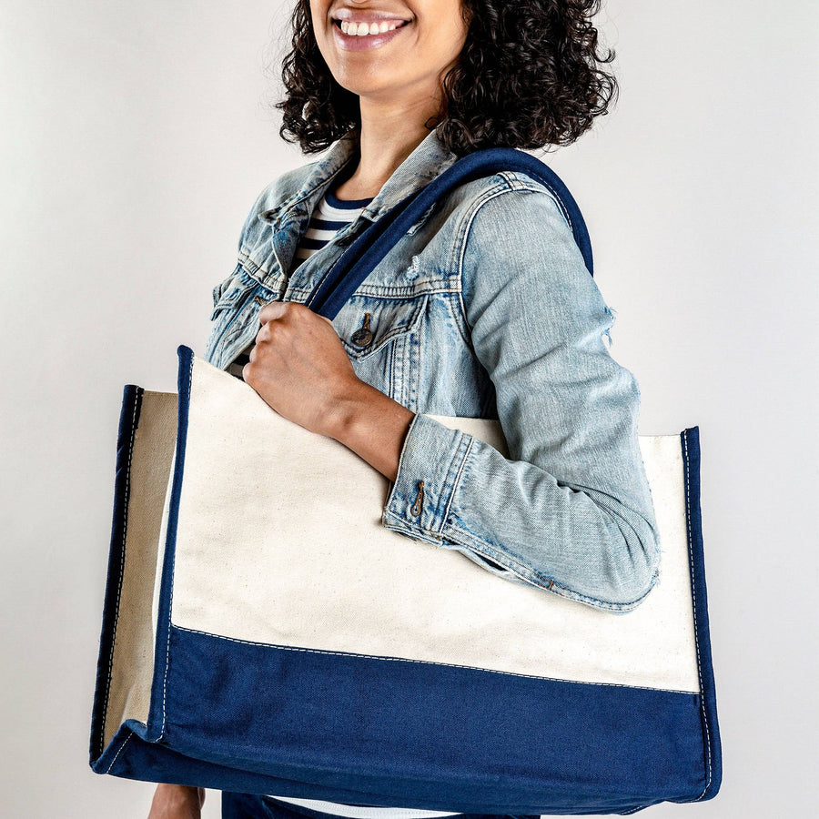Person holding a blue and beige tote bag against a plain background