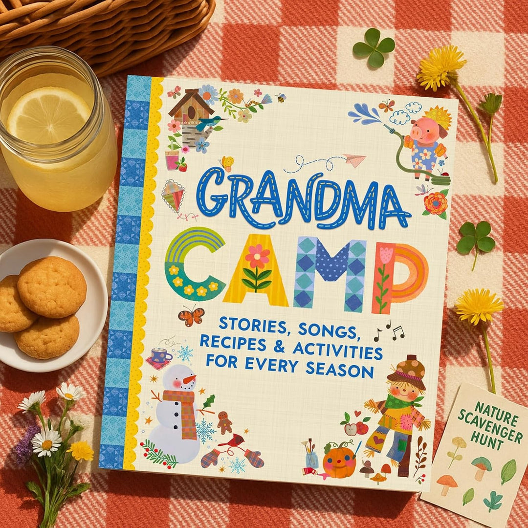 A children's activity book titled "Grandma Camp" is displayed on a red-and-white checkered picnic blanket with cookies, a glass of lemonade, flowers, and a small "Nature Scavenger Hunt" card. The cover is decorated with colorful illustrations and playful lettering.