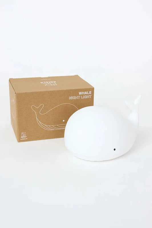 White whale night light next to its cardboard box on a white background