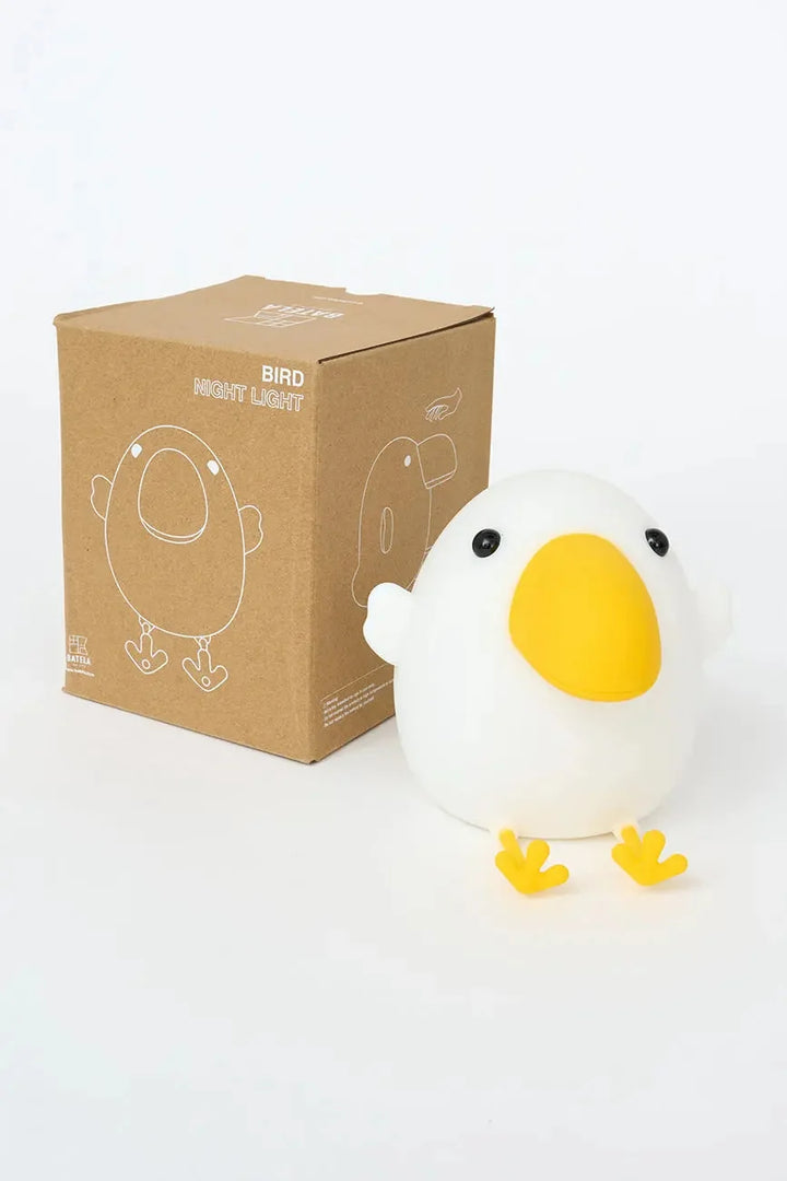 A white bird-shaped night light with a yellow beak and yellow feet stands in front of its brown cardboard packaging box on a clean white background.