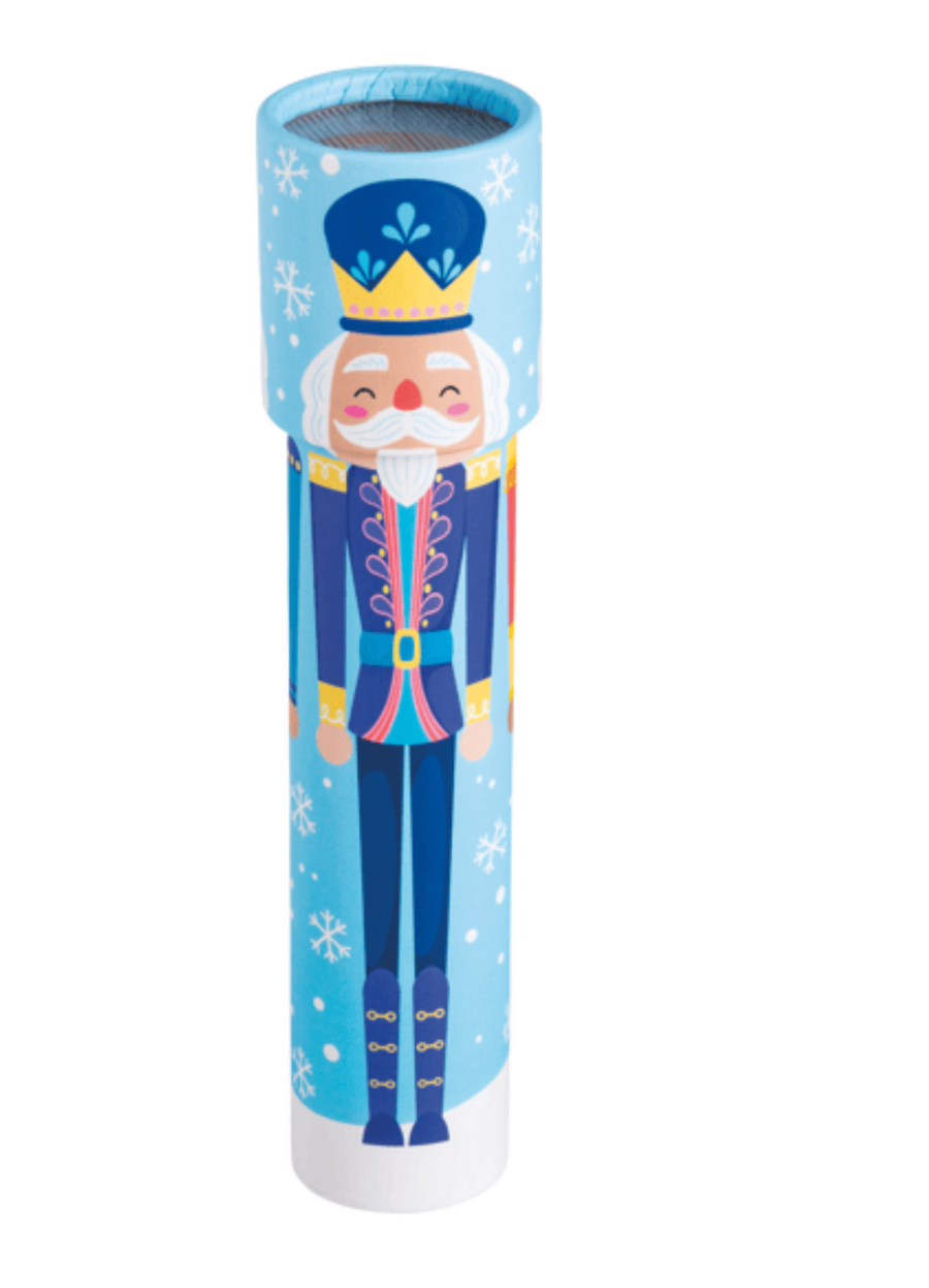 A cylindrical container or speaker with a festive nutcracker illustration on a light blue background with white snowflakes. The nutcracker is wearing a dark blue uniform with gold and pink accents, a white beard, and a blue hat with a gold crown.